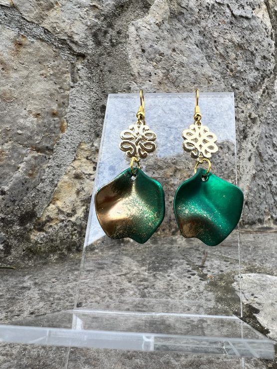 Boucles d’oreilles Flavie Découvrez les boucles d’oreilles “Flavie”, des bijoux fantaisie uniques en leur genre. Déclinées en plusieurs couleurs tendance  – blanc mat, rose métallisé, vert foncé métallisé, bleu royal mat, rouge métallisé et or – elles offrent une touche de raffinement avec leurs projections de couleur or, appliquées à la main pour une finition singulière sur chaque paire. Le design inclut un élément doré élégant et une pétale suspendue de couleur tachetée or, rendant ces boucles d’oreilles idéales pour compléter vos tenues au quotidien ou pour des occasions spéciales. Créées par l’artiste Jana Kuzmi, elles représentent un accessoire original et de qualité qui saura se démarquer dans votre collection de bijoux.